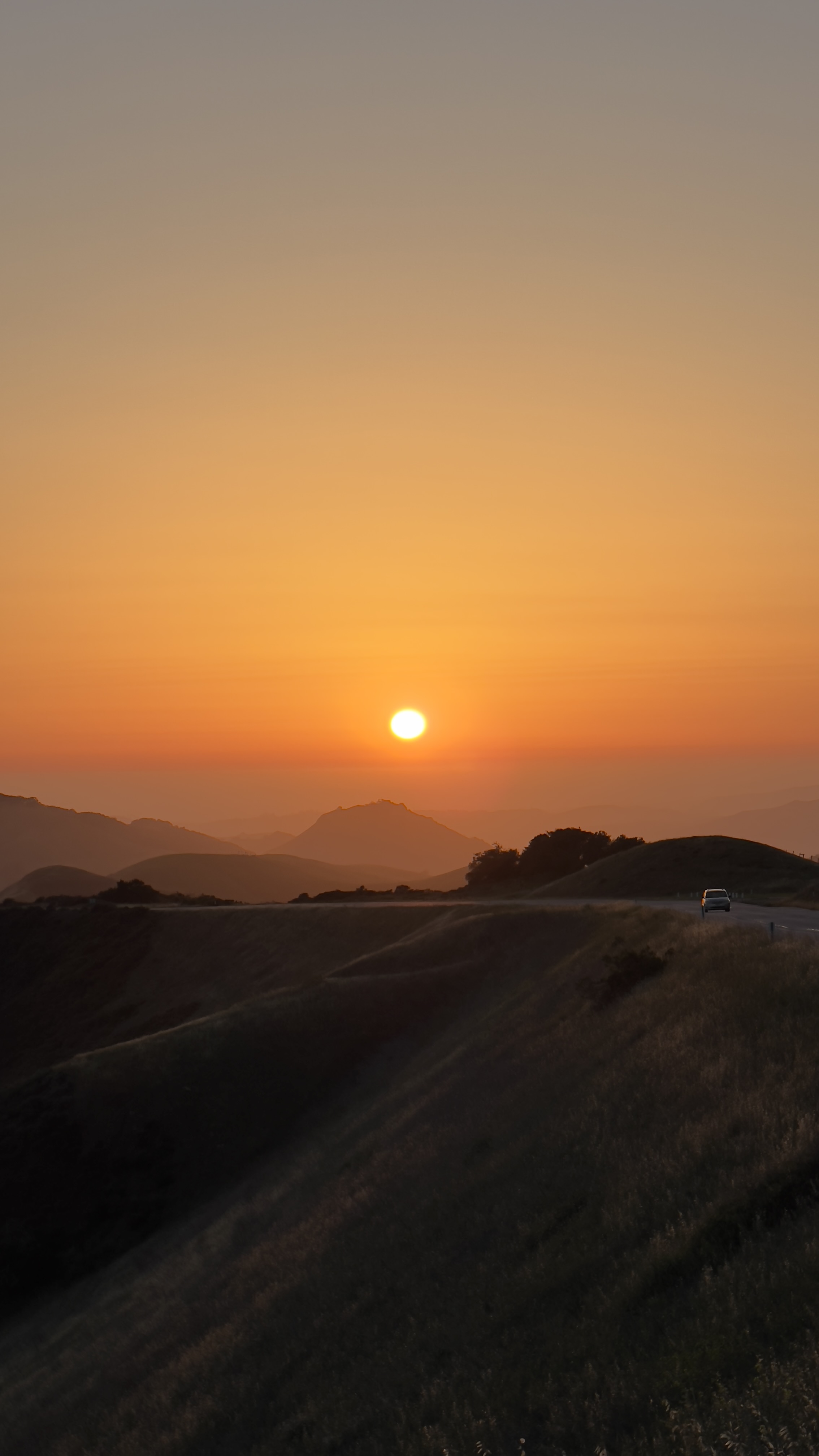 A car on a ridge at sunset